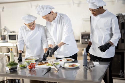 Preview: Group of cooks finishing main courses while working together in the kitchen