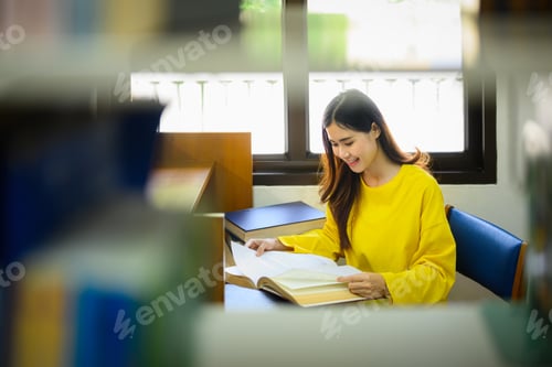 Preview: Concentrated female student reading book, doing class assignment in library.