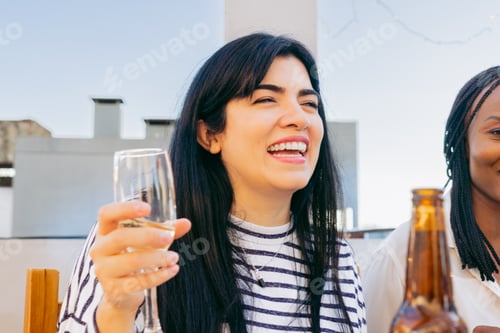 Preview: Latin woman with a glass in hand smiling on a terrace