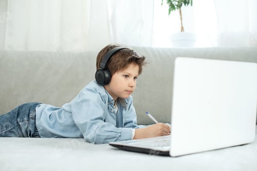 Preview: Boy in headphones study and looking on screen of laptop