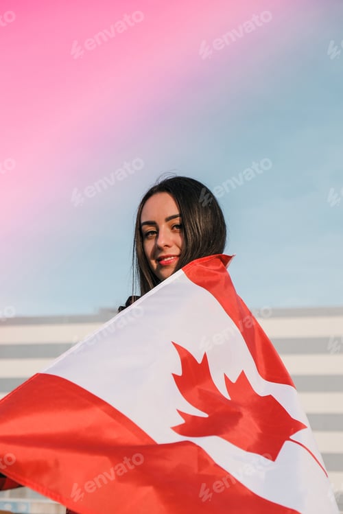 Preview: Young millennial brunette woman holding The National Flag of Canada. Canadian Flag or the Maple Leaf