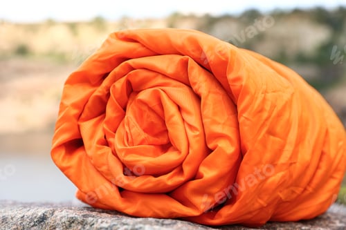 Preview: Rolled sleeping bag outdoors on sunny day, closeup