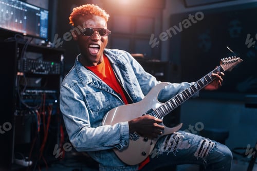 Preview: Plays guitar. Young african american performer rehearsing in a recording studio