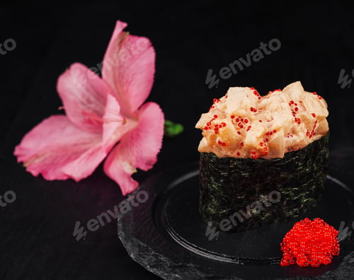 Preview: Delicious sushi topped with spicy sauce and red caviar standing on black stone plate