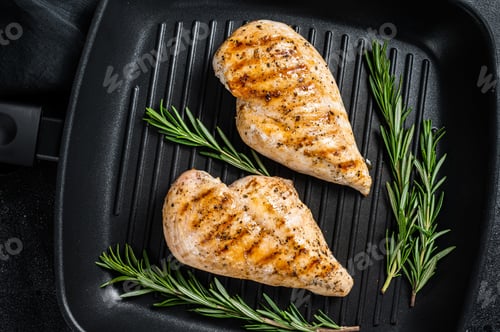 Preview: Grilled healthy chicken breasts cooked on a grill pan. Black background. Top view