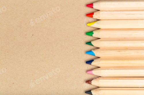Preview: Colorful pencils aligned on brown paper in a creative workspace setup during daylight hours