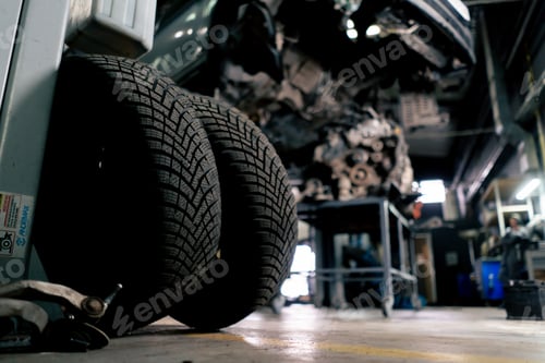 Preview: There are tires in service station in the foreground and on the table there is an elongated motor