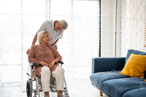 Preview: Asian active senior man support elderly woman from wheelchair to sofa.