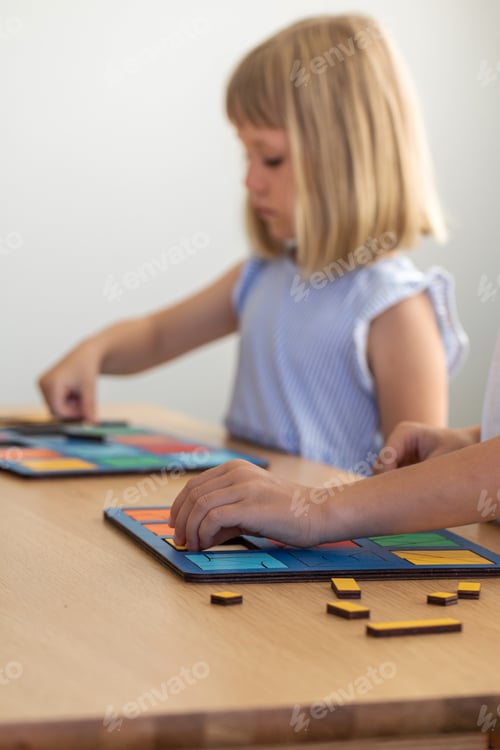 Preview: A cute girl is playing a logical wooden game at a table in a room. Children's wooden educational toy
