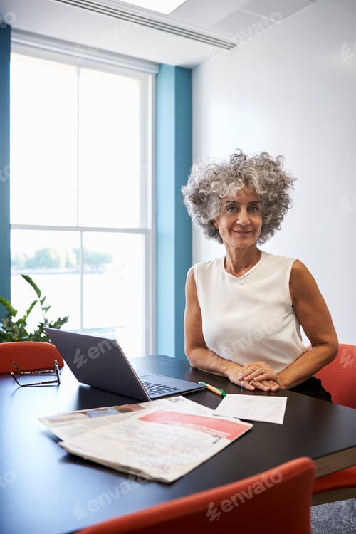 Preview: Middle aged woman in an office smiling to camera, vertical