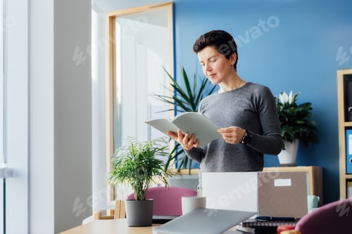 Preview: Motivated newcomer middle aged neutral gender female standing in office unpacking box