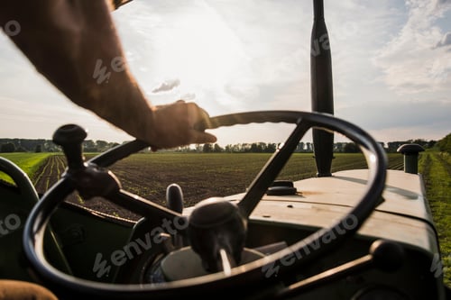 Preview: Close-up of farmer steering tractor next to field