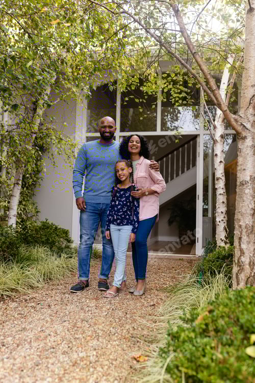Preview: Portrait of happy biracial parents and daughter embracing in garden outside house, copy space