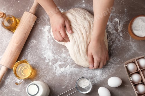 Preview: Female baker preparing bread dough at kitchen table, top view
