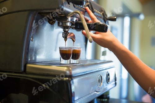Preview: A young woman making coffee using a large coffee machine.