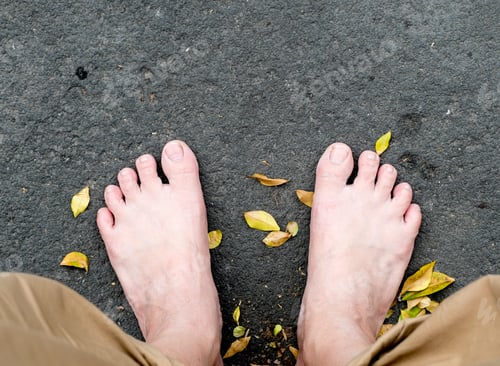 Preview: bare foot on black stone and dried leaves