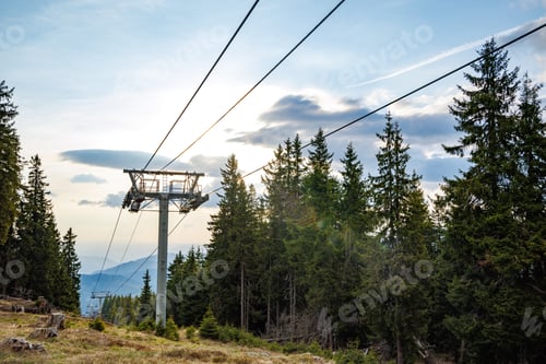 Preview: Lift with cable passes between spruce forest on peak against backdrop of Rhodope Mountains