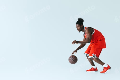 Preview: handsome african american sportsman playing basketball on grey background with copy space