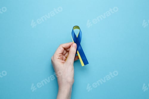 Preview: A person holds a yellow and blue awareness ribbon, symbolizing World Down Syndrome Day