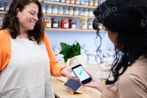 Preview: Customer making a contactless payment with smartphone in a zero waste shop