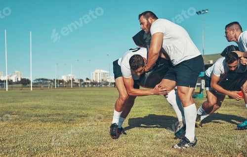 Preview: Shot of rugby players training with tackle bags on the field