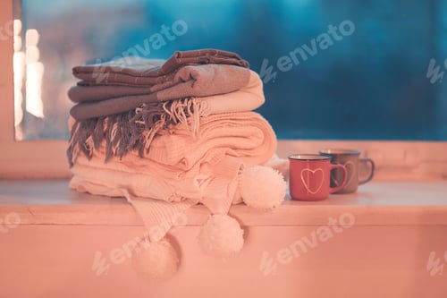 Visualização: Canecas e mantas aconchegantes na janela à noite