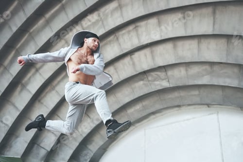 Preview: Man engaged in parkour jumping on the street workout