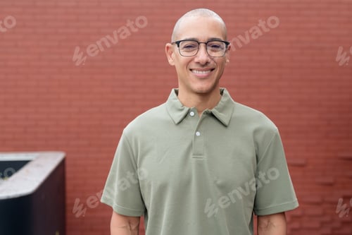 Preview: Hispanic bald man in polo shirt outdoors against brick wall