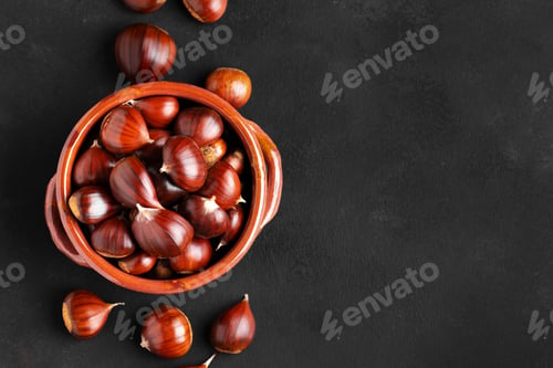 Preview: Fresh chestnuts in a clay bowl on black background