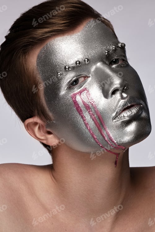 Preview: Young man with art creative art make-up with silver paint on his face.