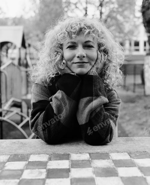Preview: Monochrome portrait of smiling woman on chessboard outdoors.