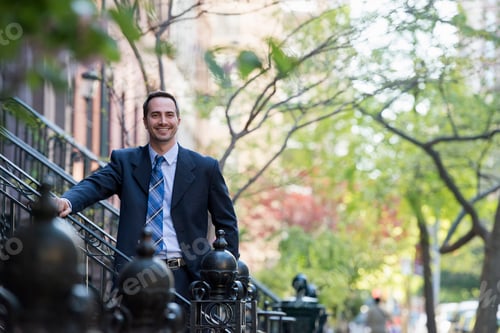 Preview: A man in a business suit standing on a street.
