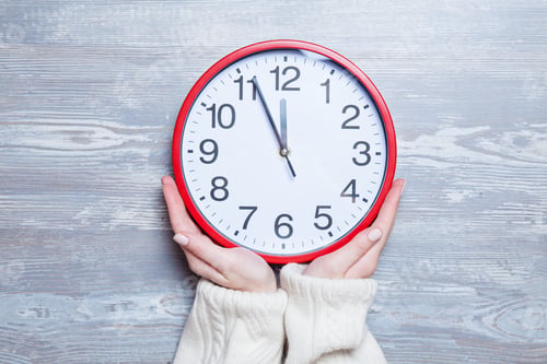 Preview: Female hands holding clock on a table.