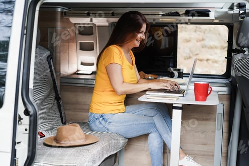 Preview: Happy senior woman using computer laptop inside camper mini van - Focus on face