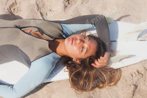 Preview: Young woman sunbathing on surfboard, Hermosa Beach, California, USA