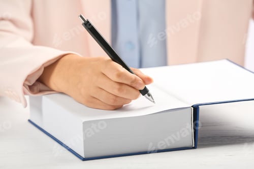 Preview: Writer signing autograph in book at table, closeup