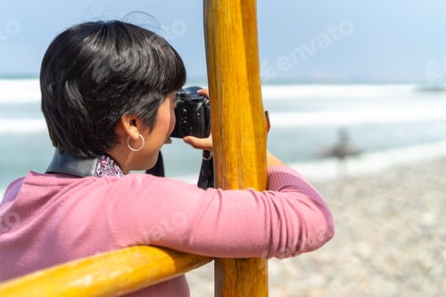Preview: Woman taking pictures standing on the beach