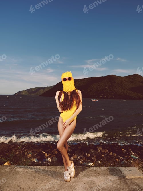 Preview: A woman in a yellow swimsuit stands near a serene lake under a clear blue sky, surrounded by lush