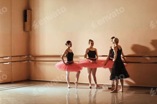 Preview: Teenage ballerinas and their teacher standing at ballet studio and talking.