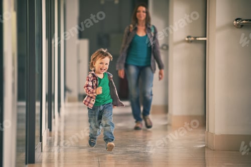 Preview: Little boy running in the shopping center with his mom on background.