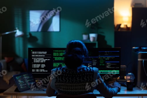 Preview: Young Woman Coding on Computer Monitors in Dark Home Office Setting