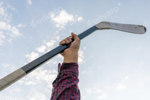 Preview: man hand holding a hockey stick against the sky, abstract sport equipments