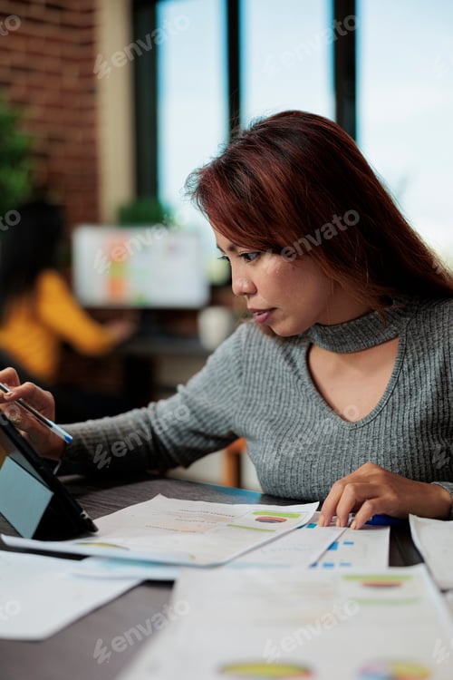 Preview: Portrait of asian entrepreneur analyzing marketing graphs on tablet