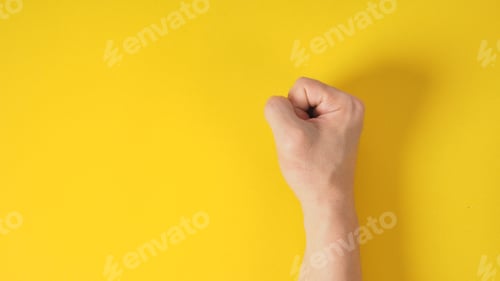 Preview: fist hand is isolated on yellow background.