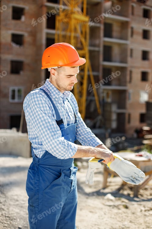 Preview: Worker in orange helmet at a construction site wearing gloves
