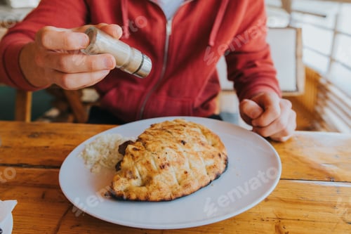 Preview: Man adding pepper on a traditional Bosnian dish called cevapi