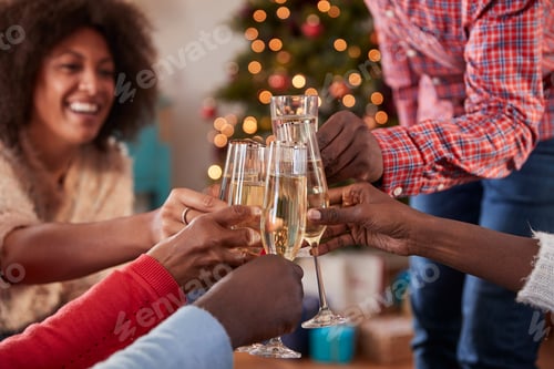 Preview: Close Up Of Friends Making A Toast With Champagne As They Celebrate Christmas At Home Together
