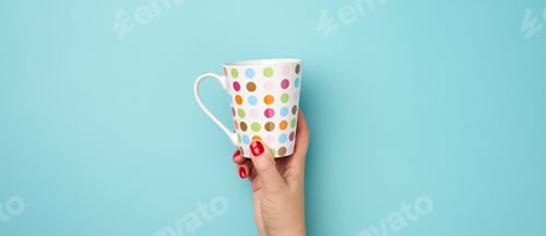 Preview: Female hand holds a ceramic mug on a blue background, break time and drink coffee