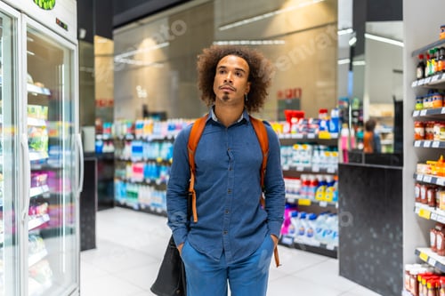 Preview: Young man thoughtfully shopping in modern supermarket aisle