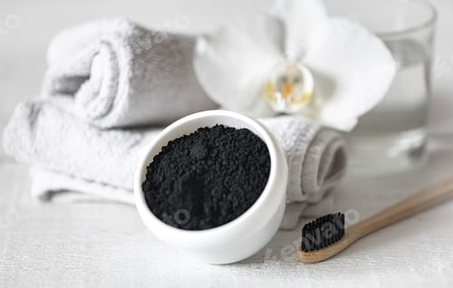 Preview: Close up of black natural teeth whitening powder and toothbrush.